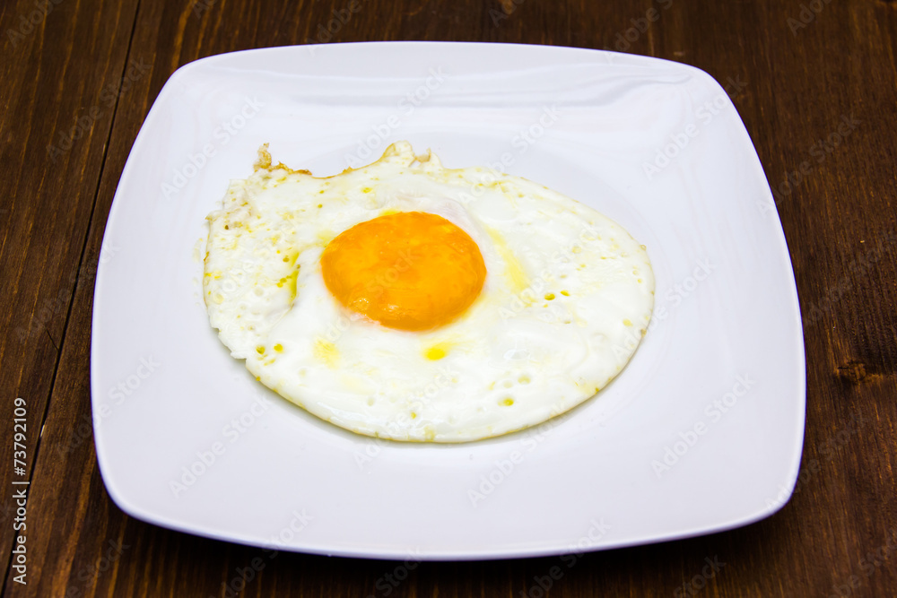 Fried egg on plate on wooden table Fried egg on plate on wooden table