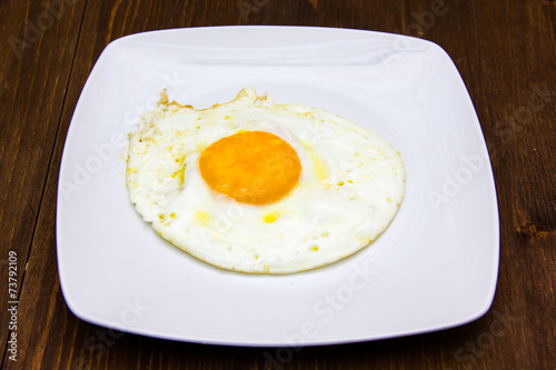 Fried egg on plate on wooden table