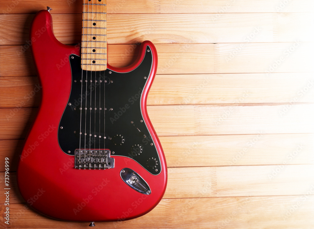 Red guitar on wooden background