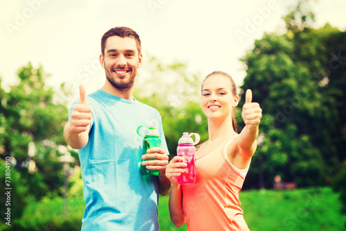 smiling couple with bottles of water outdoors © Syda Productions