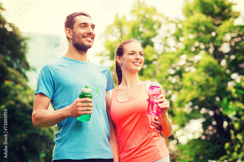 smiling couple with bottles of water outdoors