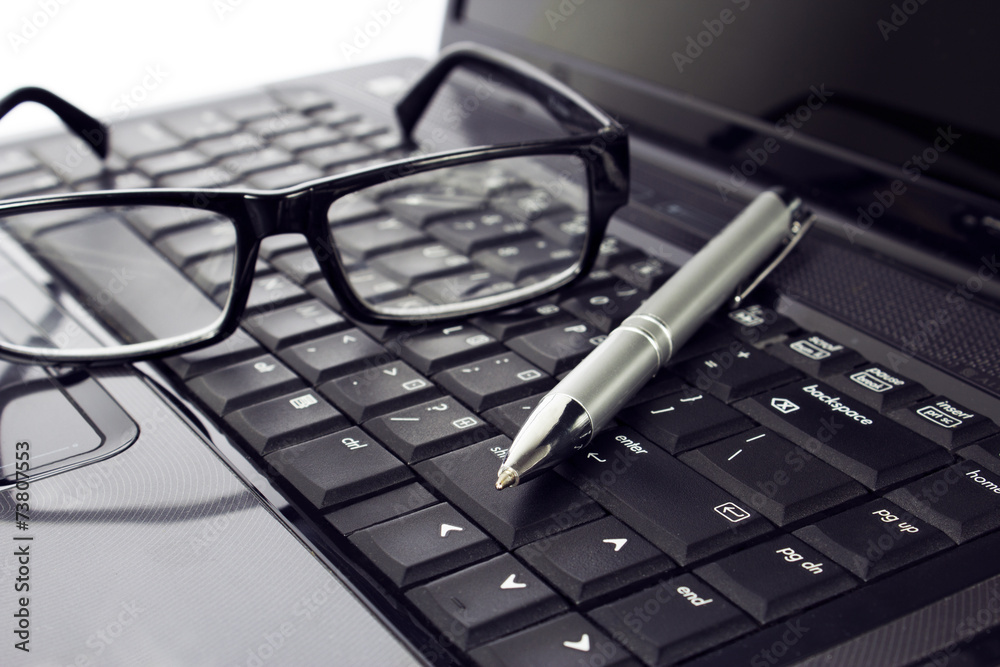 Businessman's glasses and pen on laptop computer Businessman's glasses and pen on laptop computer