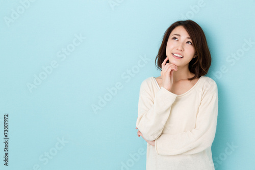 attractive asian woman thinking on blue background photo