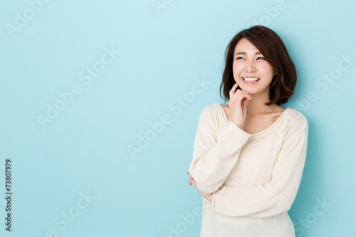 attractive asian woman thinking on blue background