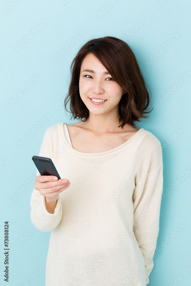 attractive asian woman using smart phone on blue background attractive asian woman using smart phone on blue background