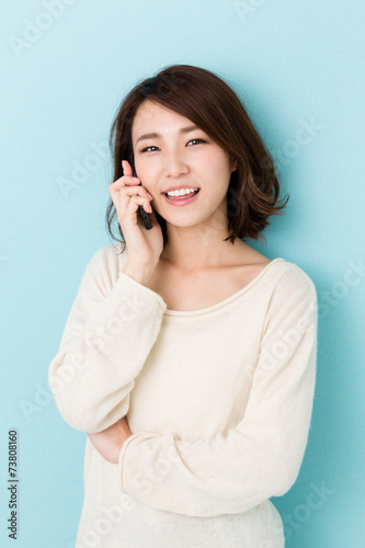 attractive asian woman talking on blue background © taka