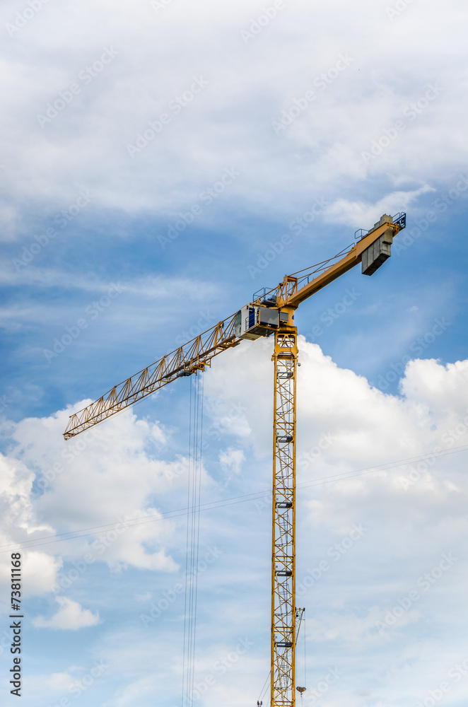 Part of yellow construction tower crane arm against blue sky Part of yellow construction tower crane arm against blue sky