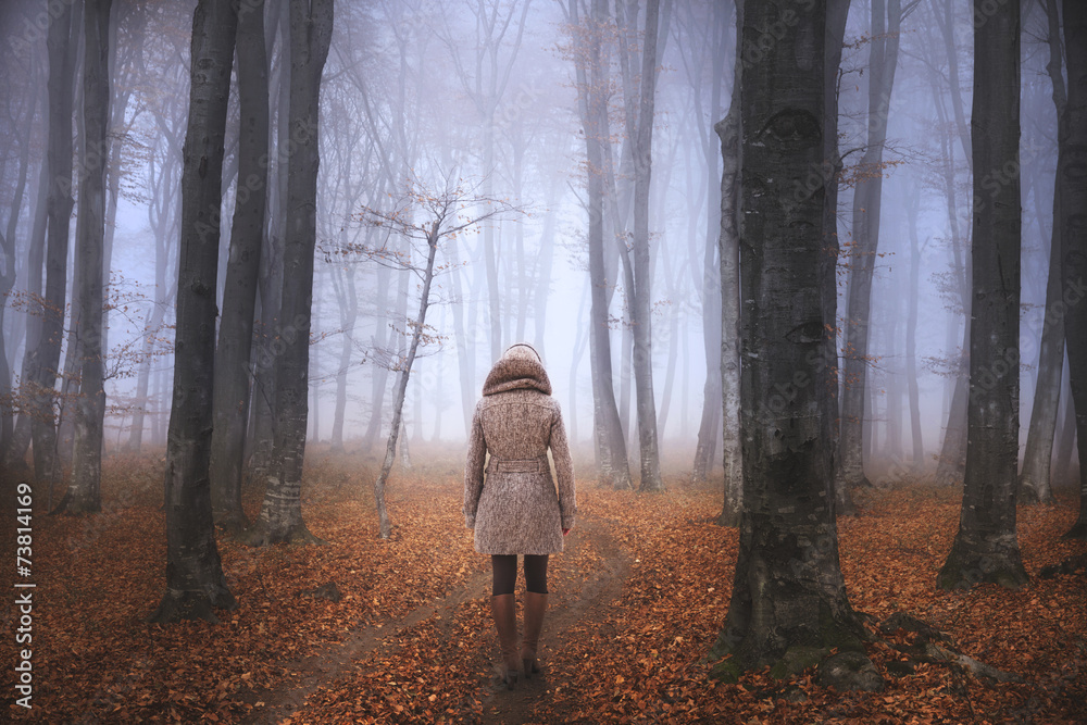 Fototapeta premium Woman in fairytale foggy forest during autumn