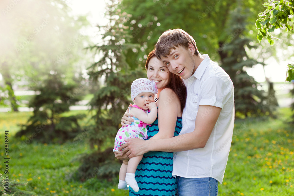 Happy young family with child resting outdoors in summer park Happy young family with child resting outdoors in summer park