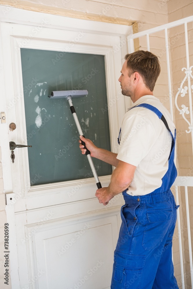 Handyman cleaning the window with squeegees Handyman cleaning the window with squeegees