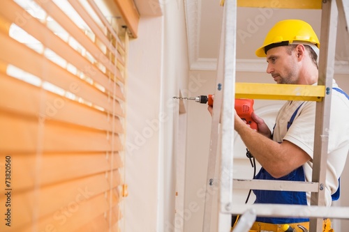 Construction worker drilling hole in wall