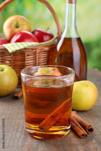 Apple cider in glass and bottle, with cinnamon sticks and fresh