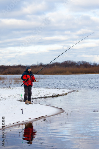 Fisherman standing on the river with fishing rod