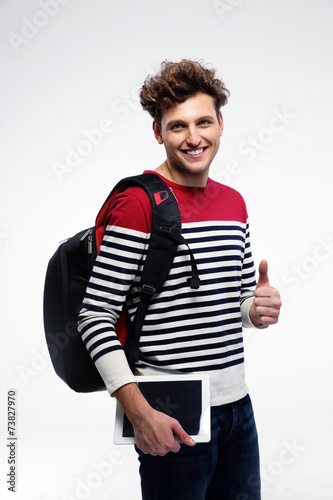 Young smiling student with backpack over gray background