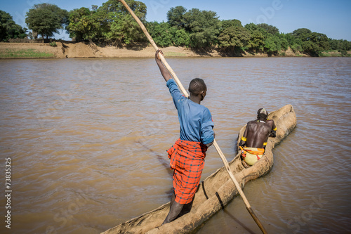 Men cross the Omo River near Turmi using a wooden boat, Ethiopia