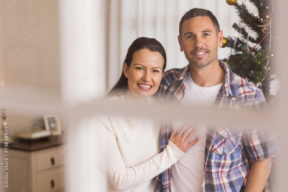 Smiling couple cuddling near the christmas tree Smiling couple cuddling near the christmas tree