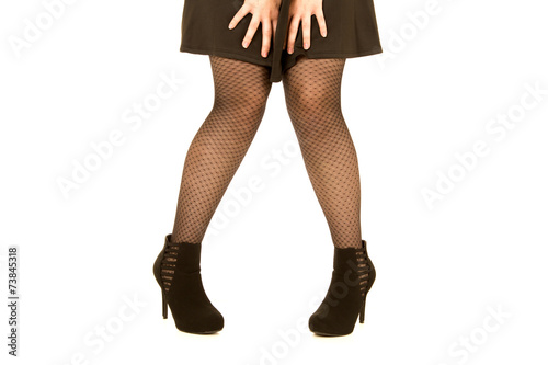 womans legs wearing black dress and fishnet stockings