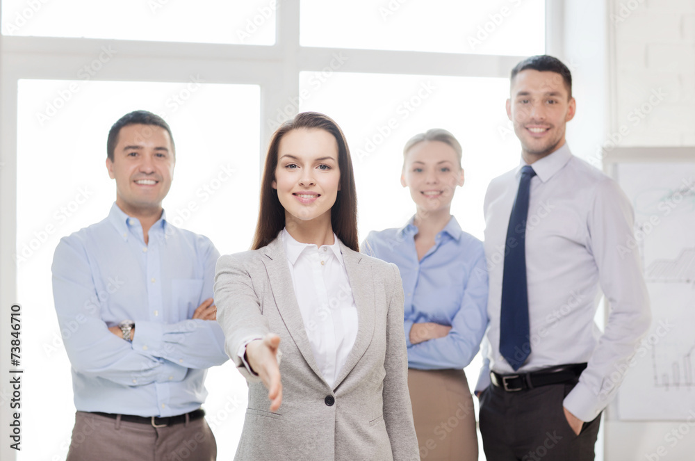 smiling businesswoman in office with team on back