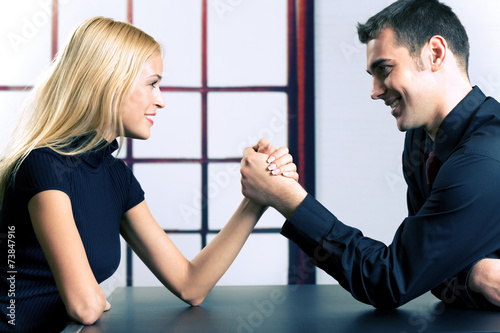 Couple or businesspeople fighting in arm-wrestling