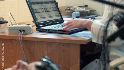 Woman having brain scan and doctor using laptop in hospital photo