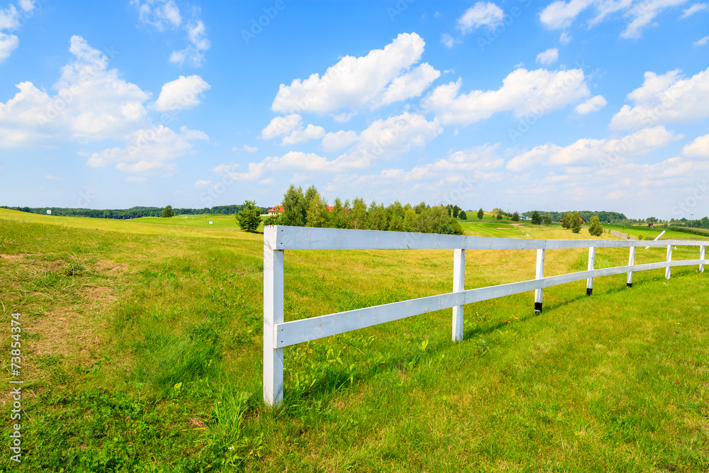 White fence on green field on sunny summer day, Poland White fence on green field on sunny summer day, Poland