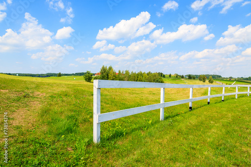 White fence on green field on sunny summer day, Poland