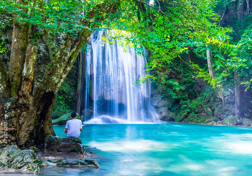 A man look at waterfall while sitting under the tree