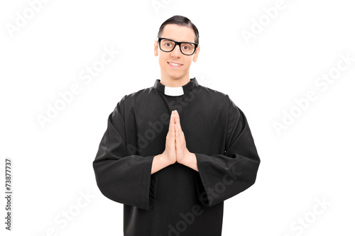 Quadro em tela Young priest praying and looking at the camera
