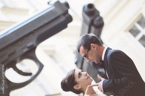 Bride and groom in the city near two giant gun pistols