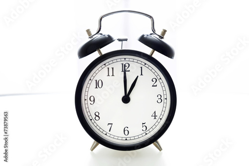 Oldfashioned black glossy alarm clock showing 1 o'clock