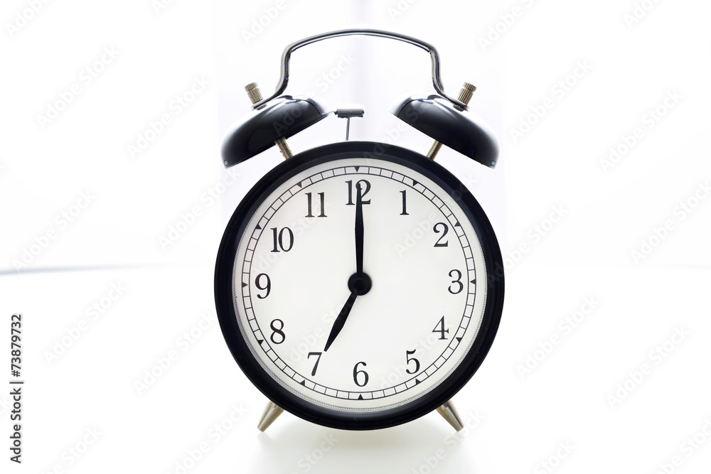 Oldfashioned black glossy alarm clock showing 7 o'clock Oldfashioned black glossy alarm clock showing 7 o'clock