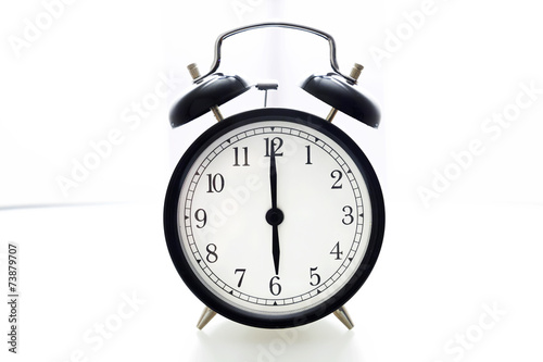 Oldfashioned black glossy alarm clock showing 6 o'clock