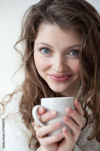 Attractive woman with a cup of coffee on the bed