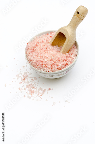 bowl, bath salts in pink, spoon, grains of salt fallen isolated