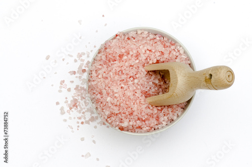 bowl, bath salts in pink, spoon, grains of salt fallen isolated