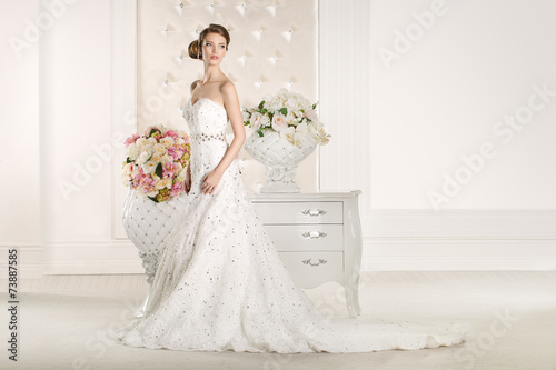 Gorgeous bride with white dress with flowers bouquet photo