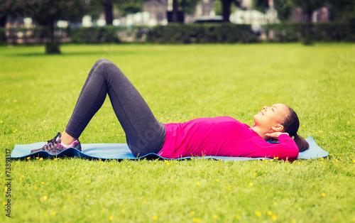 smiling woman doing exercises on mat outdoors