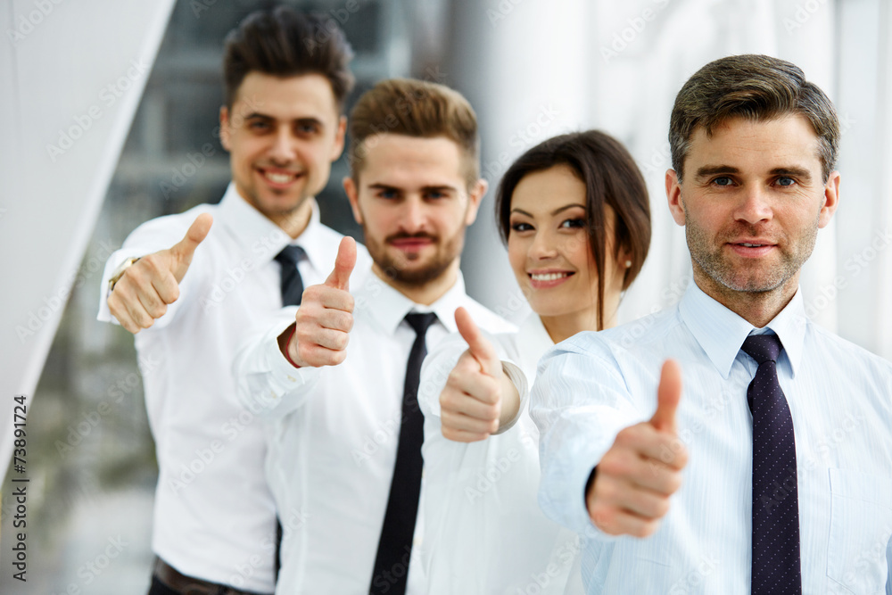 Successful young business people showing thumbs up Successful young business people showing thumbs up