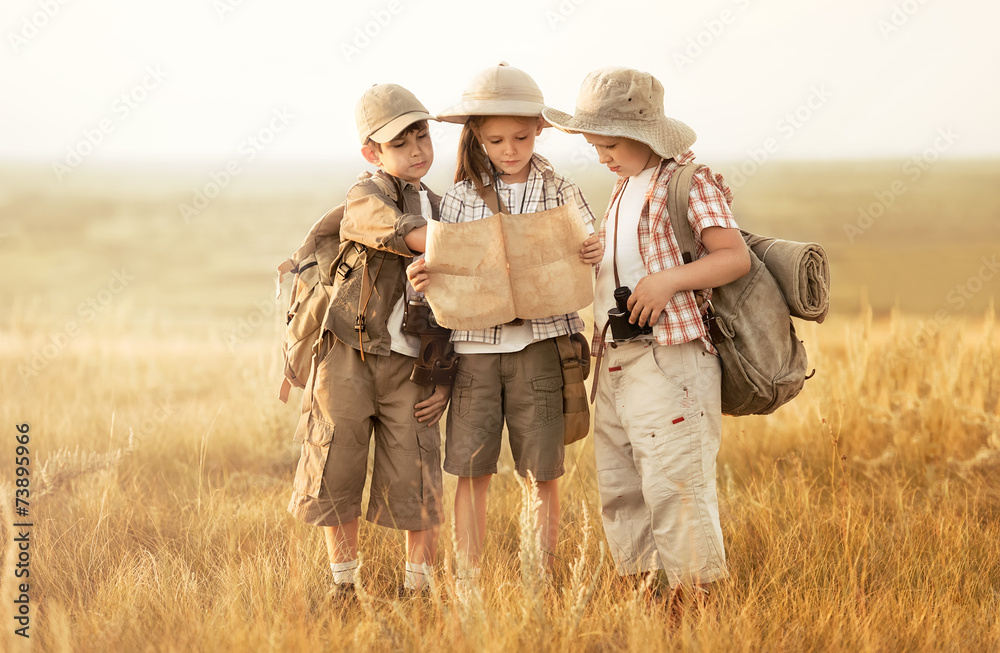 Group of kids travelers read a map at sunset - obrazy, fototapety, plakaty 