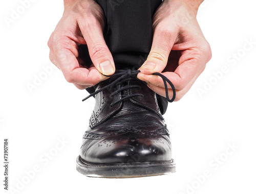 Closeup of male hands tying shoe laces on black leather shoes we