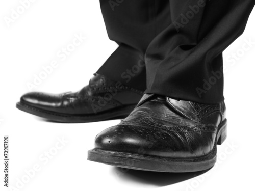 Masculine suit wearing black shoes towards white