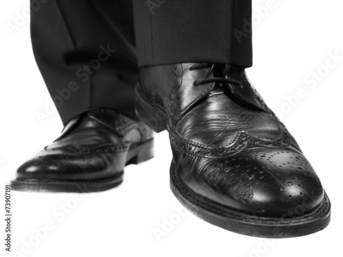 Person in black suit and shoes lifting one foot towards white