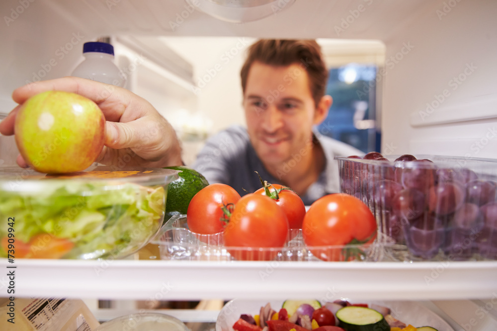 Man Looking Inside Fridge Full Of Food And Choosing Apple Man Looking Inside Fridge Full Of Food And Choosing Apple
