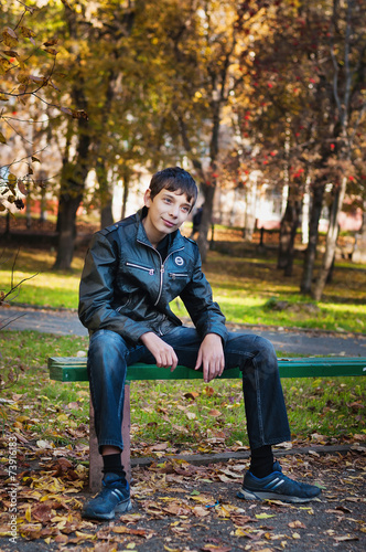 Teenager sitting on a bench in autumn park