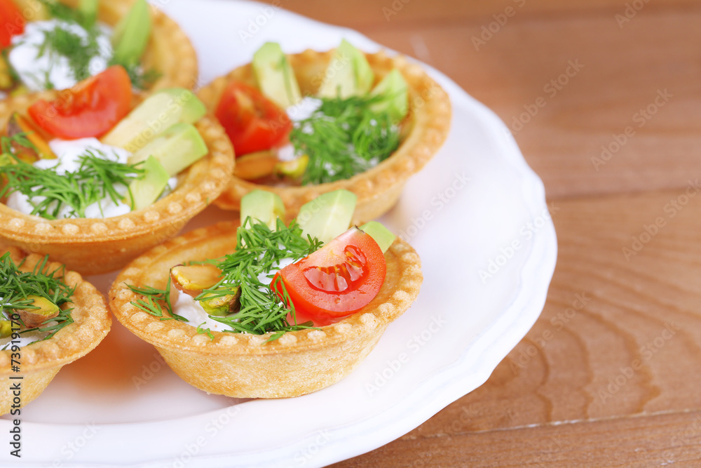 Tartlets with greens and vegetables with sauce on plate on Tartlets with greens and vegetables with sauce on plate on