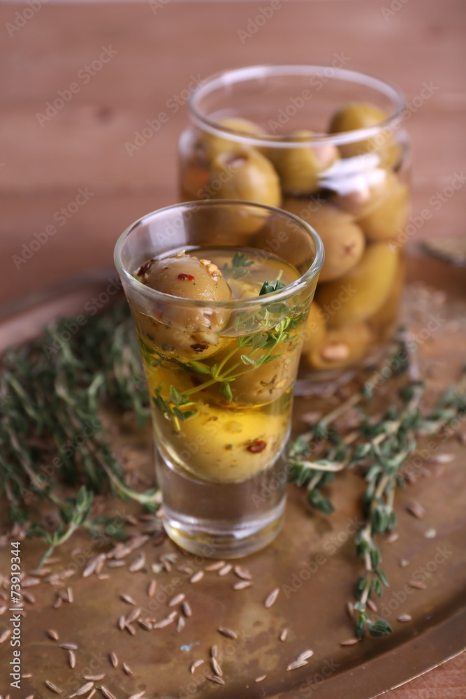 Green olives in oil with spices and rosemary in glass jars Green olives in oil with spices and rosemary in glass jars