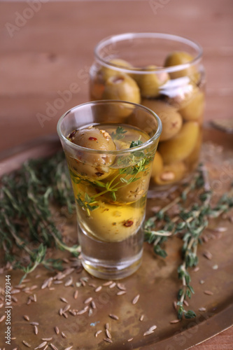 Green olives in oil with spices and rosemary in glass jars