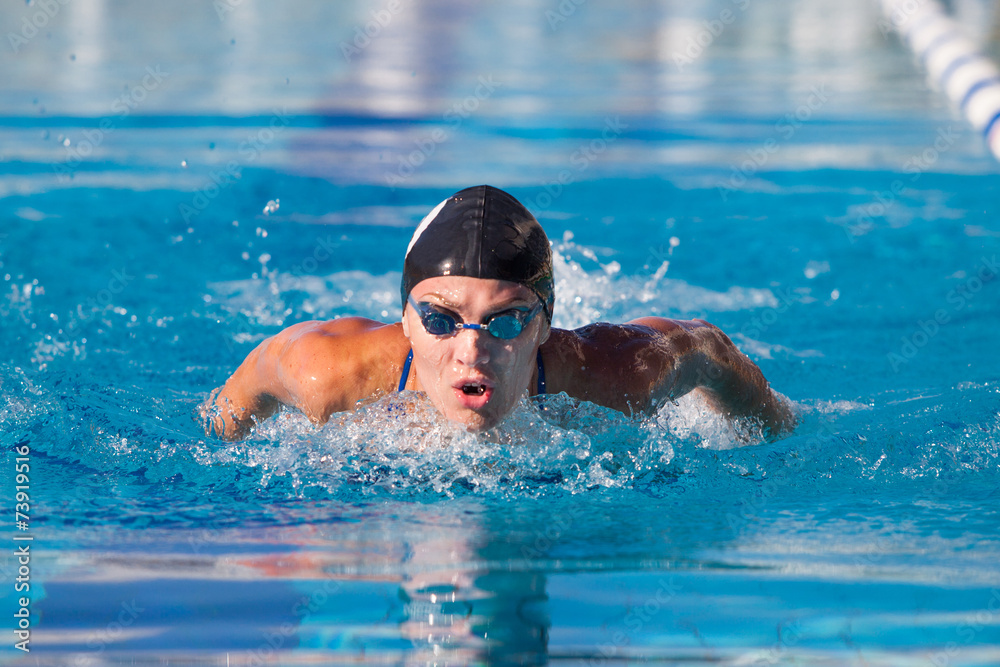 Butterfly swimmer in cap and glasses in the pool