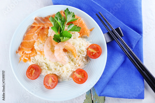 Boiled rice and shrimps, salmon on plate, on wooden background