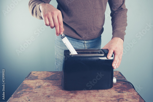 Young man sticking knife in toaster photo